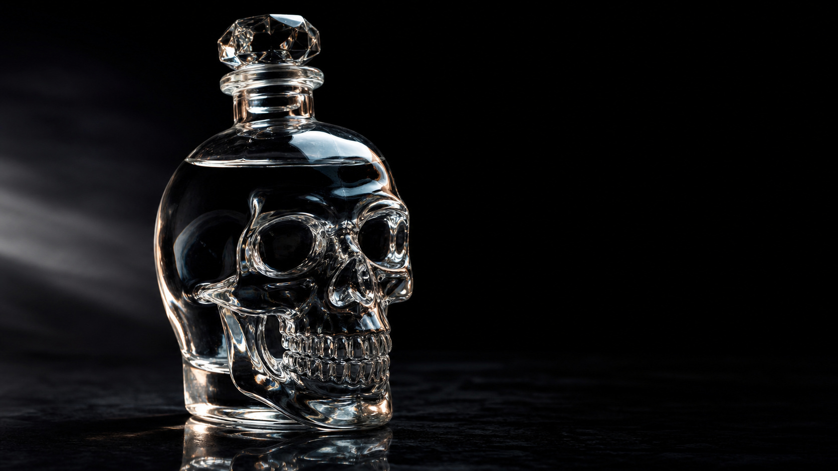 Crystal Head Vodka in kristallklarer Totenkopf-Flasche vor dunklem Hintergrund mit dramatischem Licht